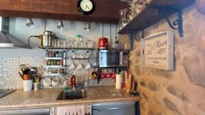 Una cocina con vigas de madera, un reloj y un cartel que indica vino local.