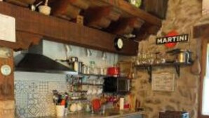 Una cocina rústica con vigas de madera, una zona de bar y un cartel que dice 'MARTINI'.