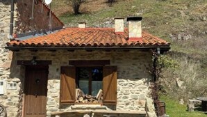 Una casa de piedra con techo de tejas rojas, antenas parabólicas y una escalera de piedra que conduce a la entrada.
