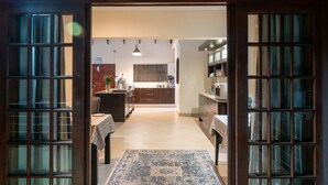 An open doorway leading to a kitchen with a tiled floor, wooden cabinets, and a central island. - Casa Albergo (Akasia)