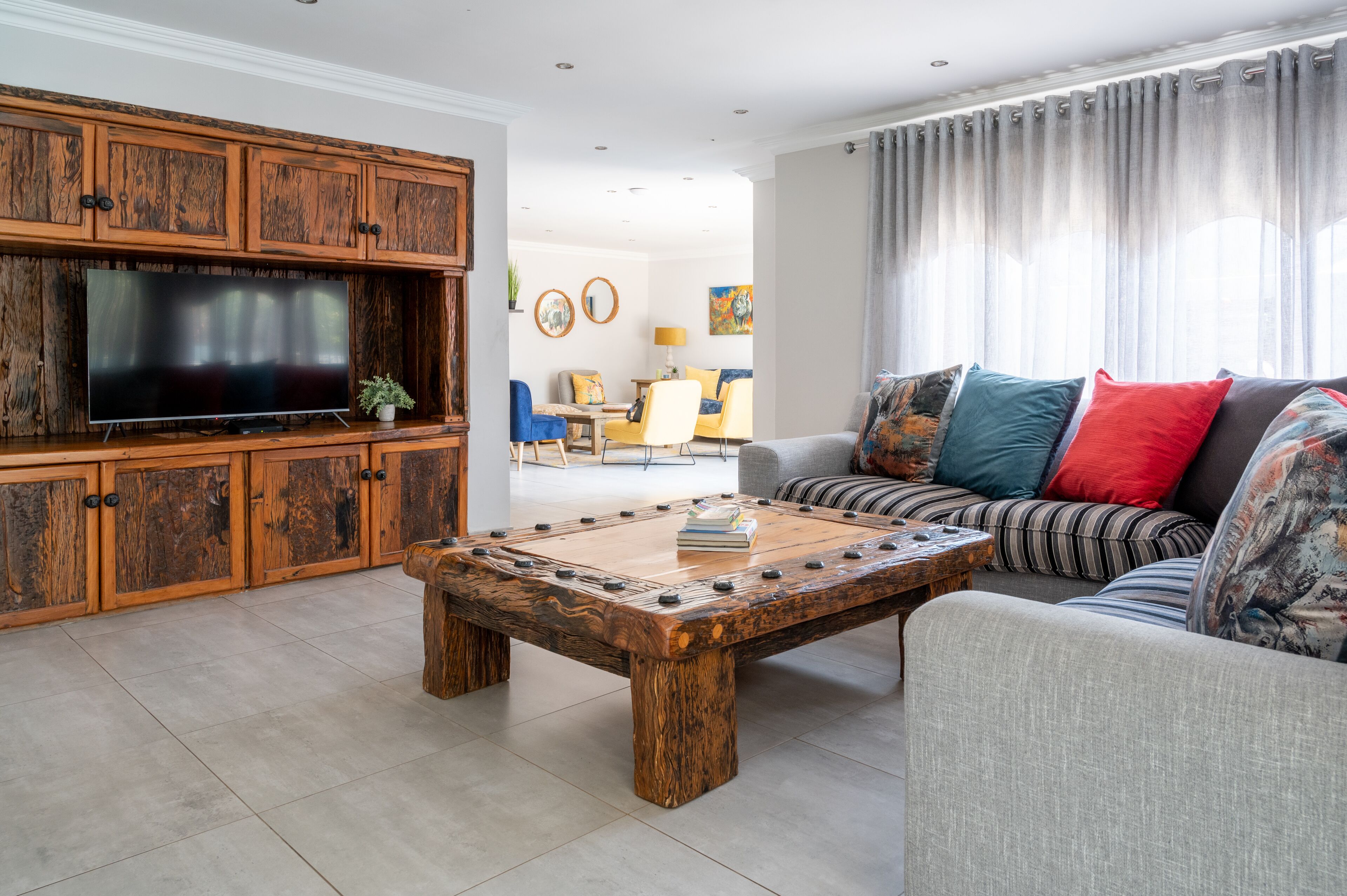 Una sala de estar con mesa de billar, un sofá con cojines de colores y un televisor.