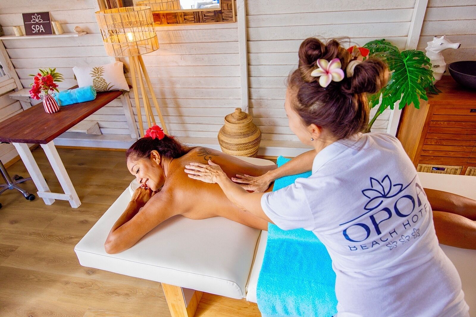 A spa setting with a massage table, a massage therapist, and a client receiving a back massage.