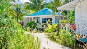 Un complexe hôtelier tropical avec un bâtiment à toit bleu, entouré d’une végétation luxuriante et de palmiers.