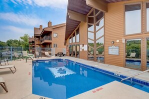 A pool area with lounge chairs and a building with a wooden facade. - Steph's Waterfront Retreat (Wisconsin Dells)