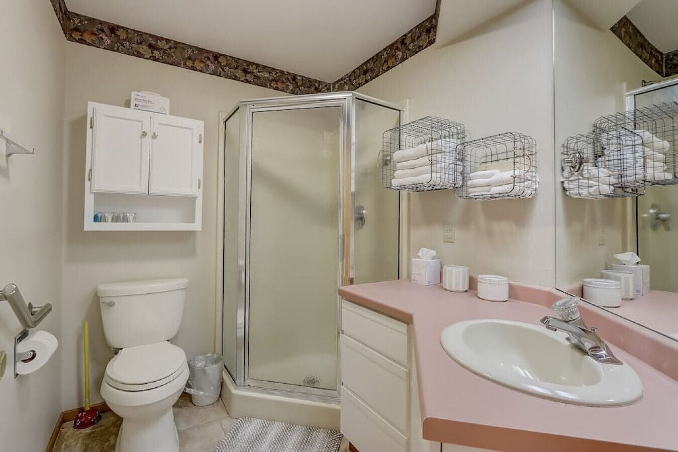 A bathroom with a toilet, shower, sink, and towel racks.