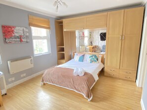 A bedroom with a bed, wooden wardrobe, and a radiator. - Immaculate Studio Apartment in Edgware Road (London)