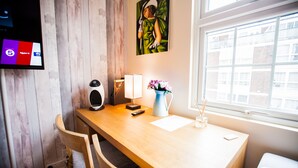 Ein Holztisch mit einer Lampe, einer Blumenvase und einem Gemälde an der Wand.