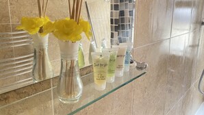 Ein Badezimmer mit einer Glasablage für Toilettenartikel, einem Spiegel und einer gefliesten Wand.