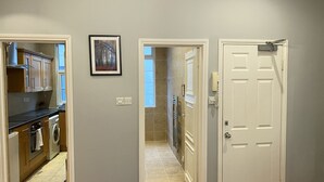 Ein Flur mit einer Küche links, einer Tür rechts und einem gerahmten Bild an der Wand.