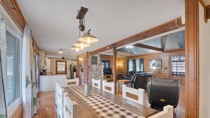 A spacious dining area with a long wooden table, white chairs, and a checkered table runner. A stone wall and wooden beams are visible in the background. - 16 Acres of beauty and relaxation  (Park Hills)