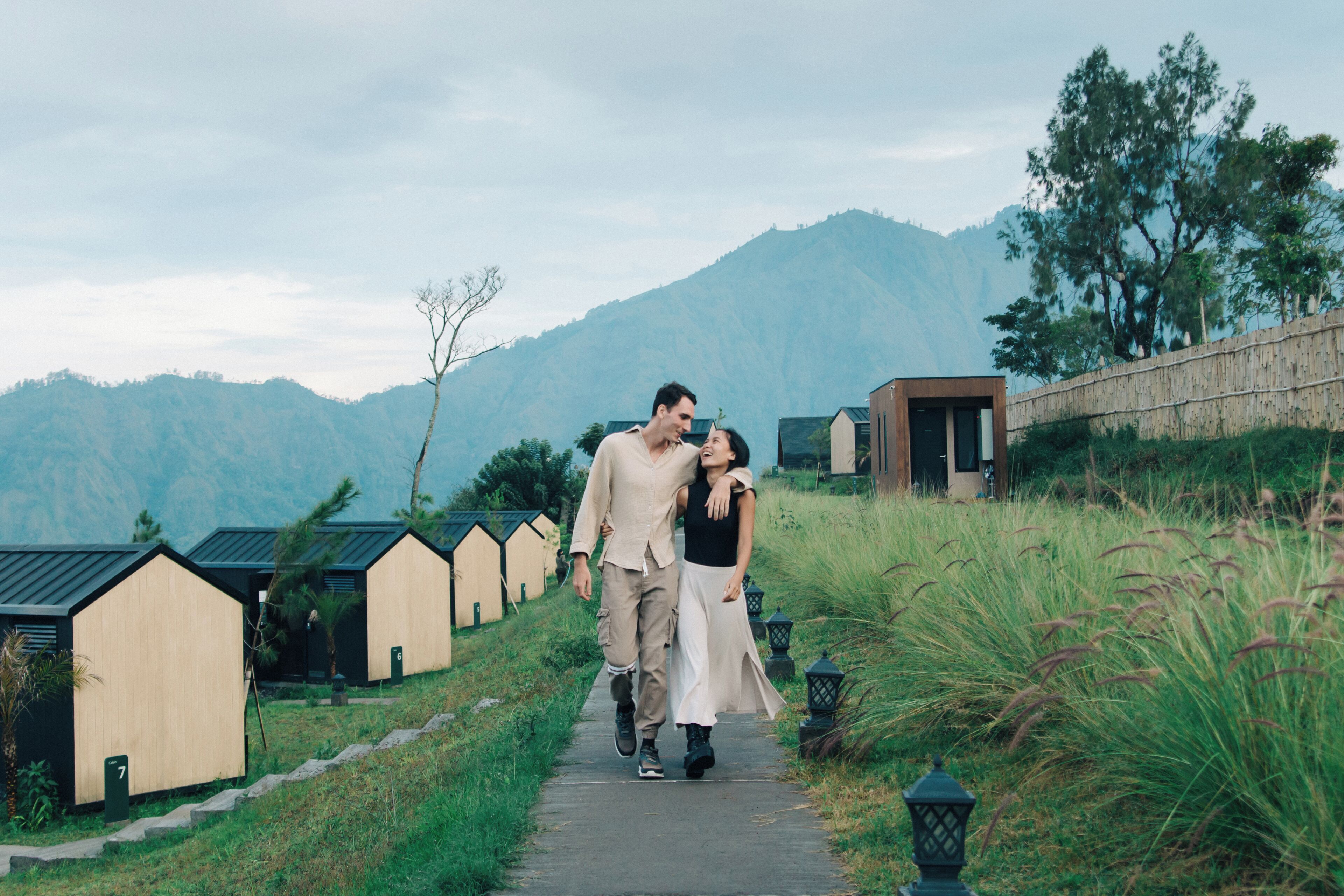 A pathway leading to wooden cabins with a mountainous backdrop.