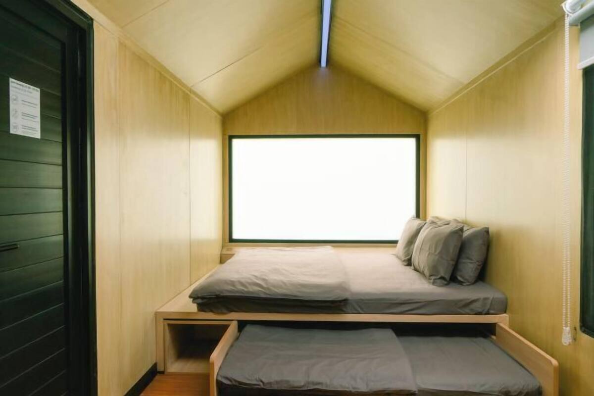 A small, compact room with a bunk bed and a window providing natural light.