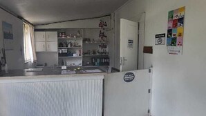 A kitchen with white cabinets, a refrigerator, and a window with curtains. - Eden Guest Farm (Bloemfontein)