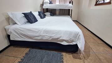 Un dormitorio con una cama individual, literas arriba y una pequeña alfombra en el suelo.