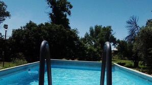A swimming pool with clear blue water, surrounded by trees and a grassy area. - Eden Guest Farm (Bloemfontein)