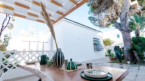 A patio with a wooden table, various decorative items, and a white building in the background. - Villa Bord de mer Piscine Chauff e et Terrasse (La Marsa)