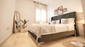 A bedroom with a bed, a mirror, a potted plant, and a bedside table. - Villa Bord de mer Piscine Chauff e et Terrasse (La Marsa)