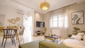 A modern living room with a sofa, a coffee table, a TV, and a dining area with chairs and a table. - Villa Bord de mer Piscine Chauff e et Terrasse (La Marsa)