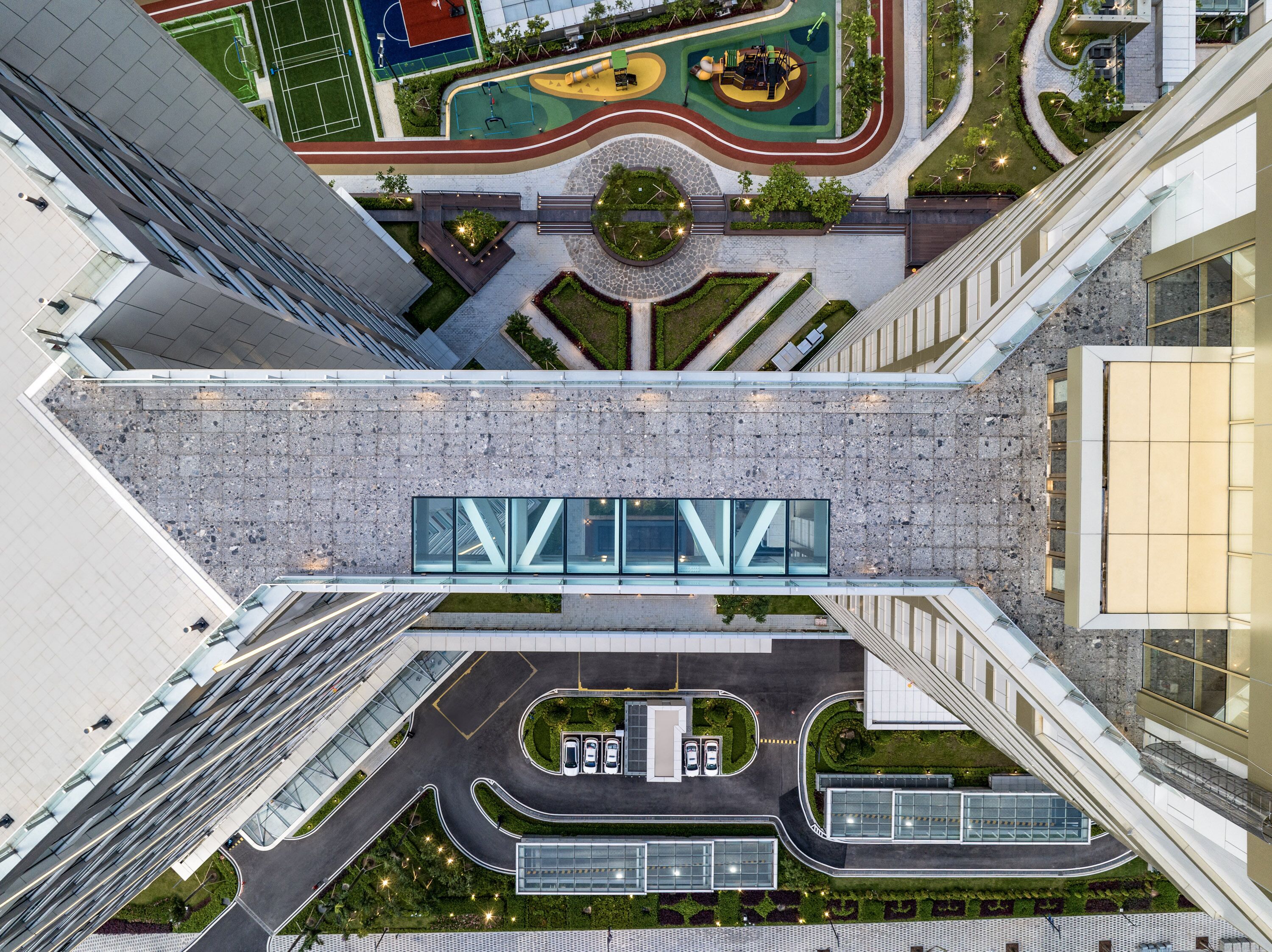 A modern building with a glass facade, a central courtyard, and a parking area.