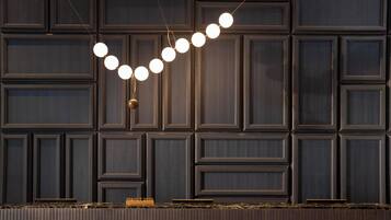A modern interior with a dark wood panel wall and a pendant light with multiple bulbs.