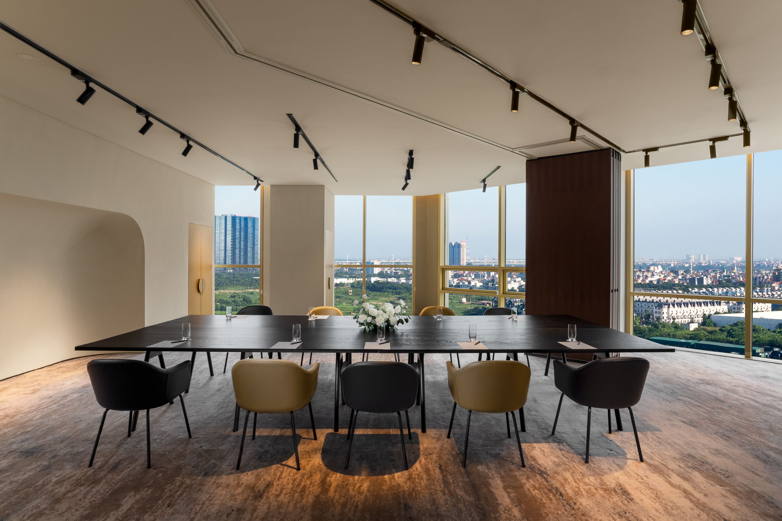 A conference room with a long table, six chairs, and large windows offering a city view.