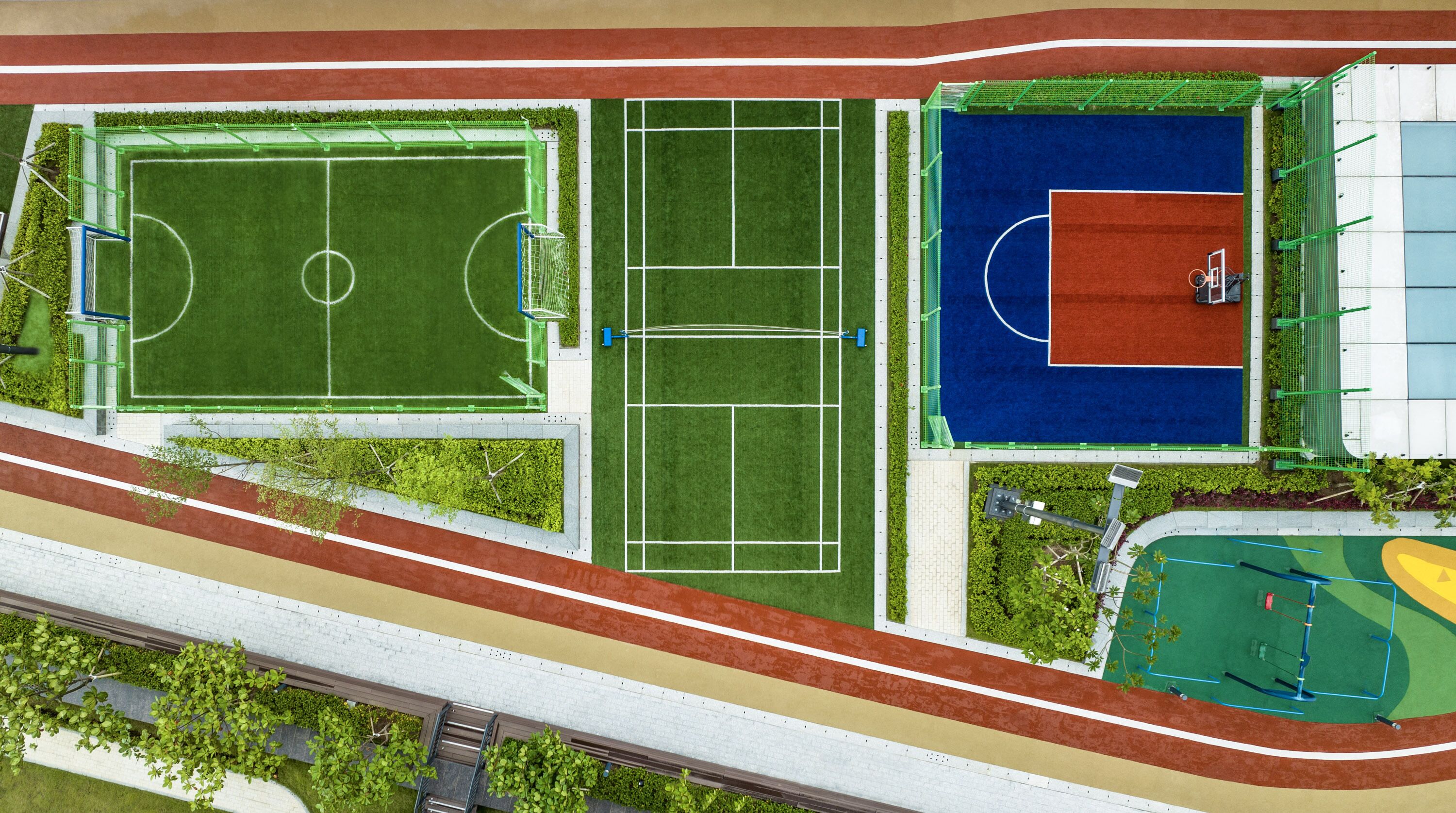 Luchtbeeld van een sportcomplex met diverse velden en speelbanen, omringd door groen en een atletiekbaan.