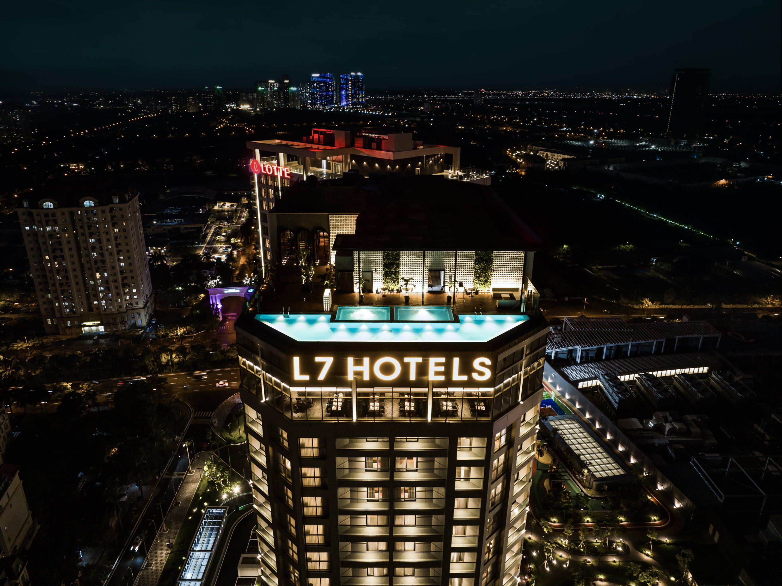 A high-rise hotel with a rooftop pool and a view of the cityscape at night.