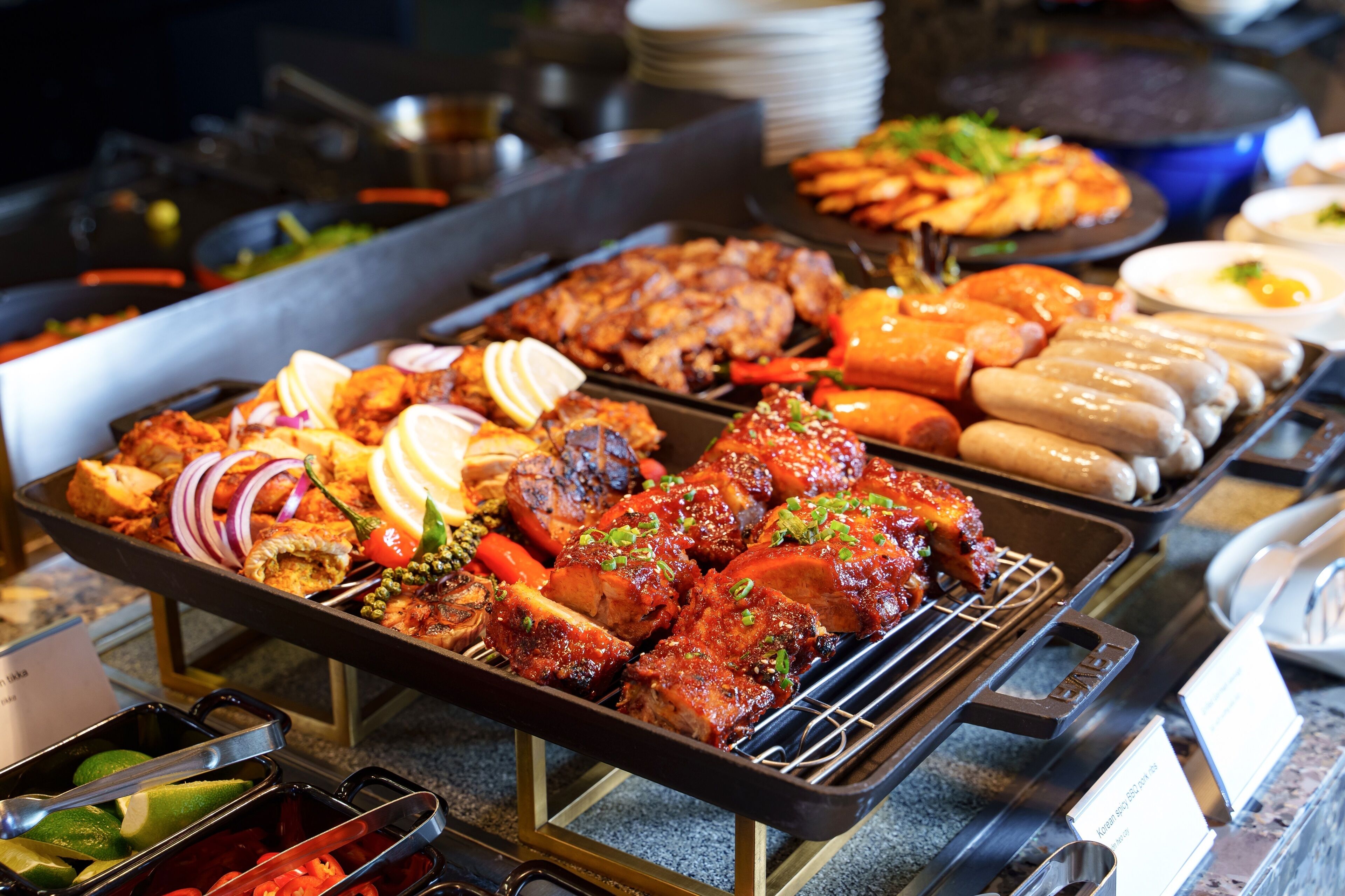 Un buffet proposant une variété de plats, notamment des viandes grillées, des saucisses et des légumes.