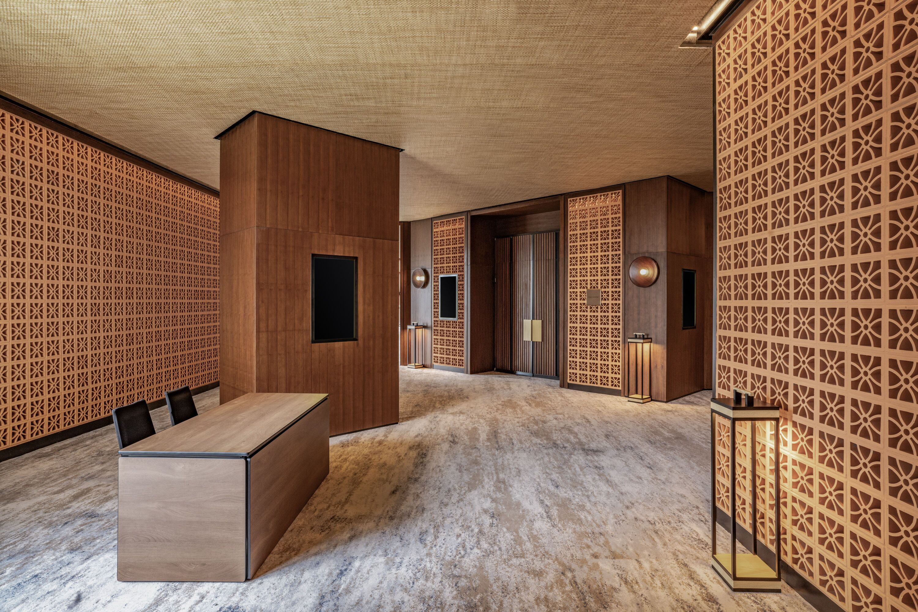 A modern conference room with a wooden reception desk, patterned walls, and a marble floor.
