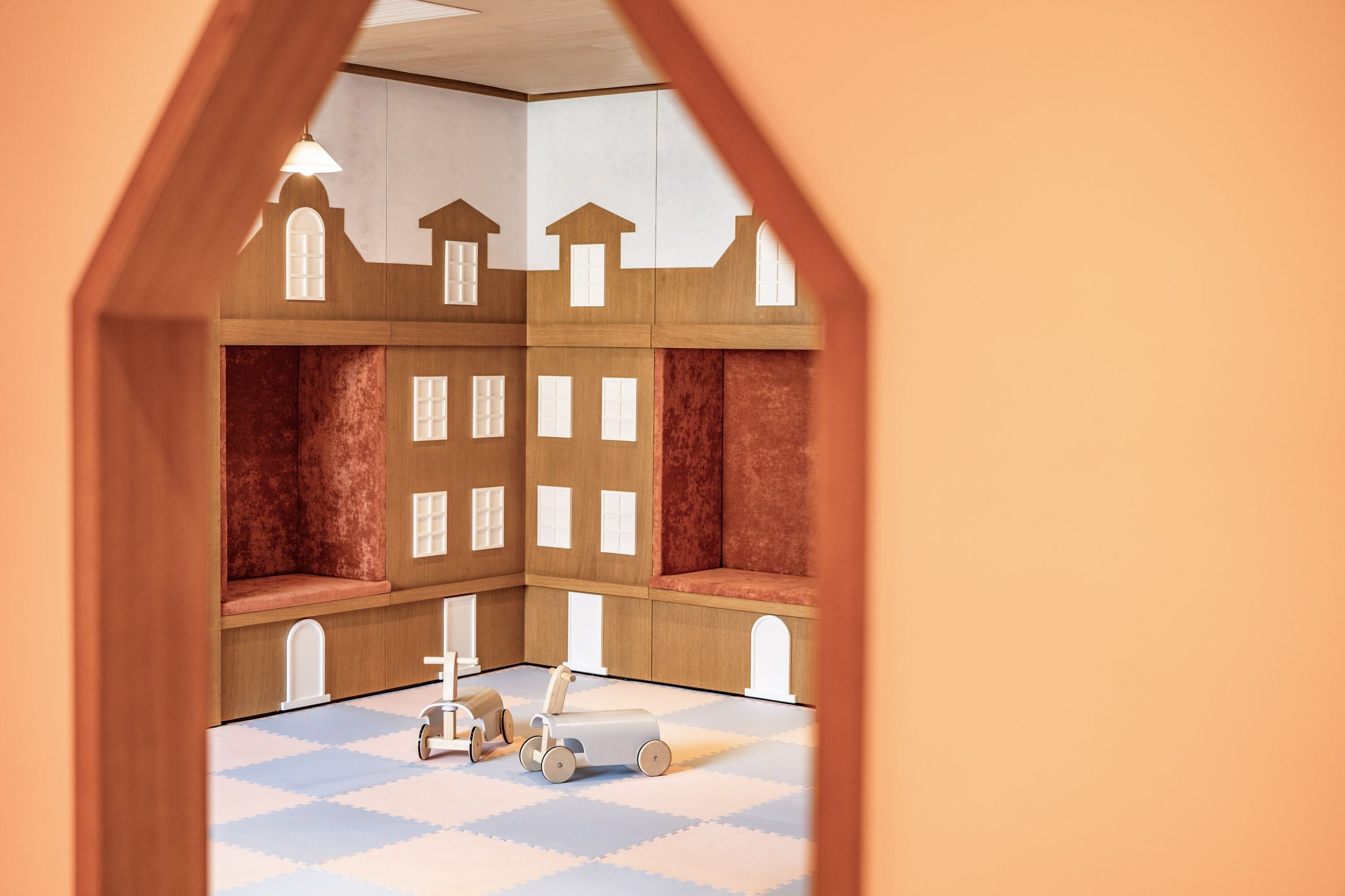 Ein Puppenhaus mit mehreren Zimmern, einem Schachbrettmuster-Boden und einem Spielzeug-Lkw.