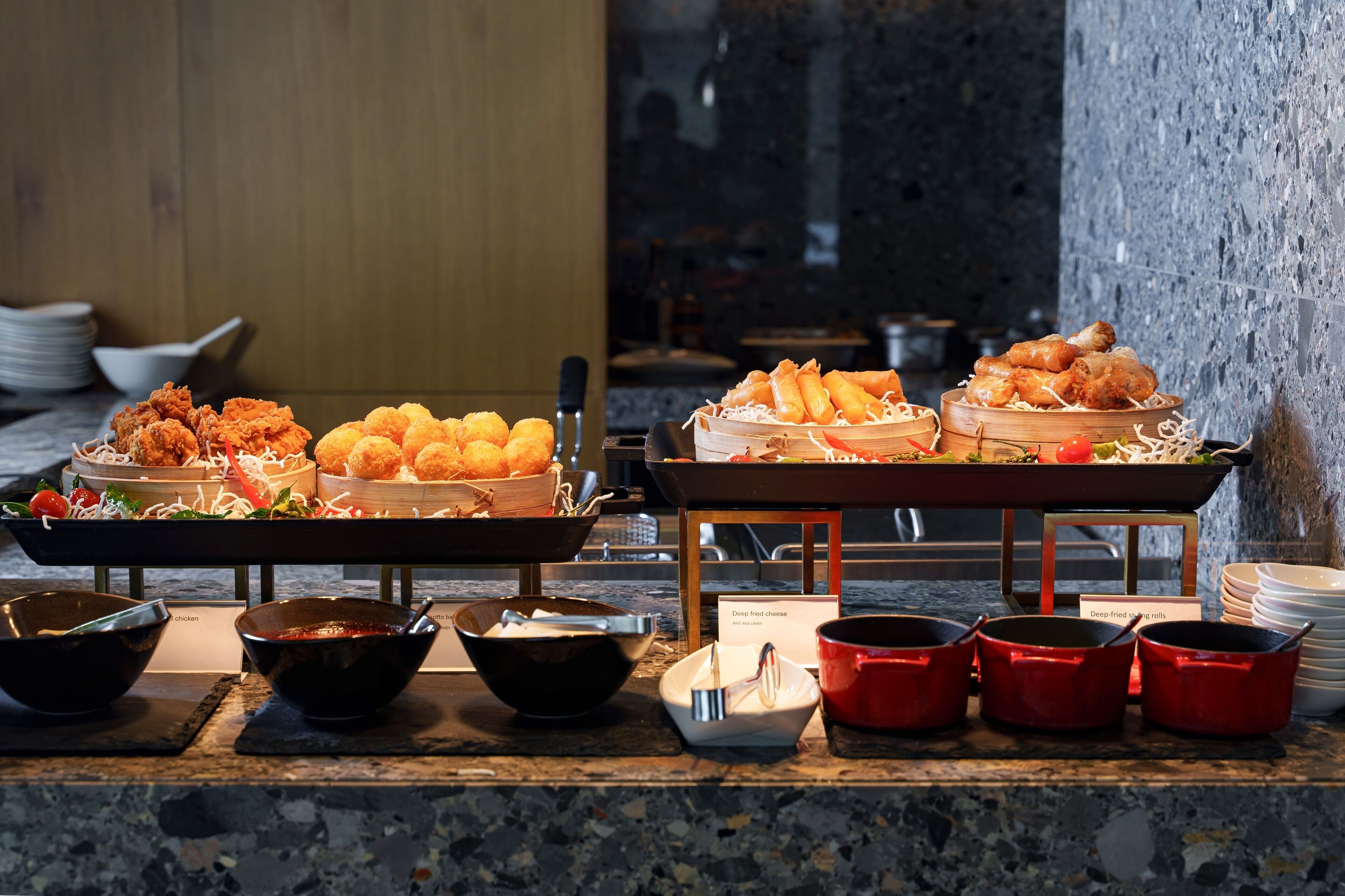 A buffet with various fried foods, bowls, and serving utensils.