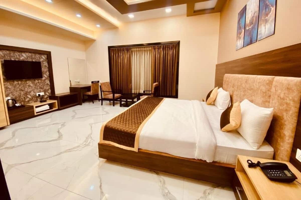 A modern hotel room with a large bed, a desk, a TV, and a bathroom area.