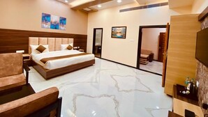 A modern hotel room with a large bed, a sofa, a TV, and a bathroom visible through an open door. - SKYWORLD Hotels and Resorts (Kuchaman)
