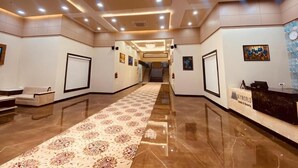 A hotel lobby with a marble floor, a reception desk, and a patterned carpet leading to a staircase. - SKYWORLD Hotels and Resorts (Kuchaman)