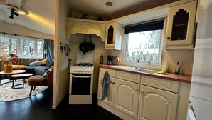 Een compacte keuken met witte kastjes, een gasfornuis en een raam met uitzicht op de omgeving.