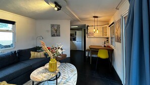 Een gezellig, ruimtelijk ingerichte zithoek met een bank, een klein tafeltje met een vaas en een eethoek met een stoel en tafel.