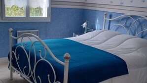 Un dormitorio con una cama, un ventanal con cortinas y una pared decorada con motivos náuticos.