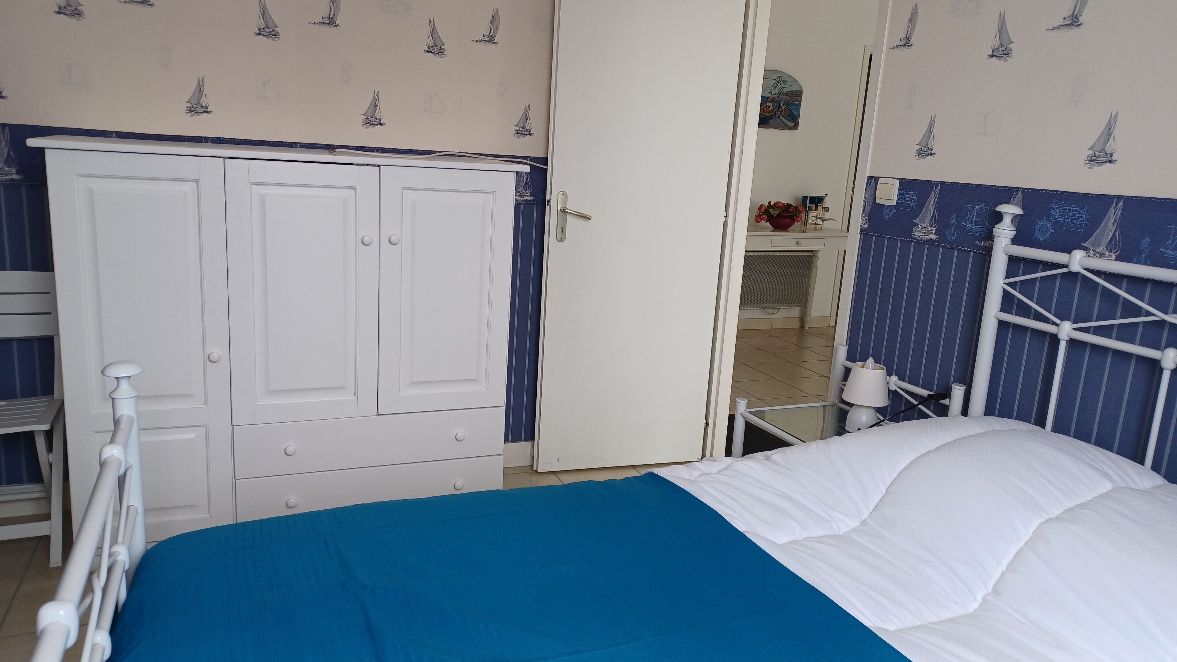 Un dormitorio con cama, armario y baño visible a través de una puerta abierta.
