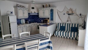 Cocina compacta con armarios blancos, salpicadero de azulejos azules y sofá a rayas.