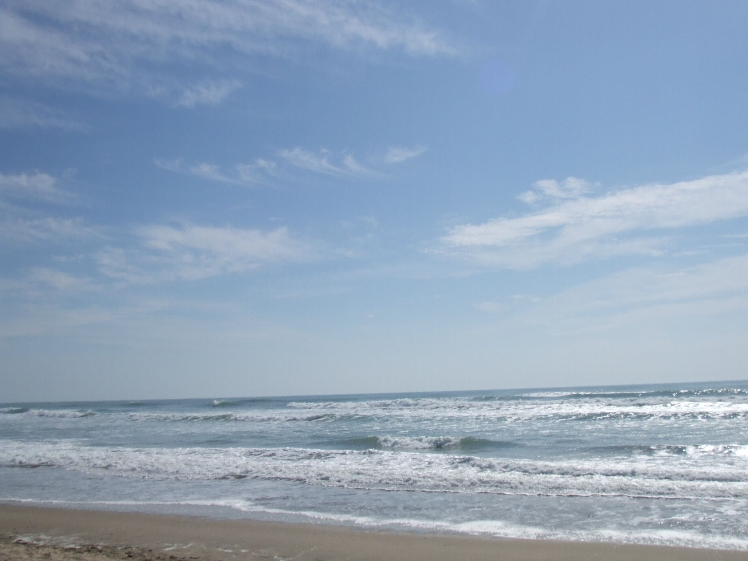 A beach with waves and a clear sky.