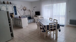 Un espacio habitable compacto con una mesa de comedor, sillas, un sofá y una zona de cocina.