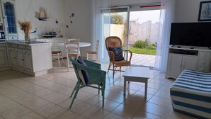 Un espacio de estar moderno con comedor, cocina y un televisor grande.