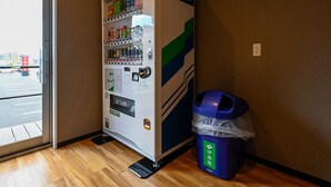 A vending machine with various drinks and snacks, a trash bin, and a door leading outside. - HOTEL R9 The Yard Fukuyama (Fukuyama)