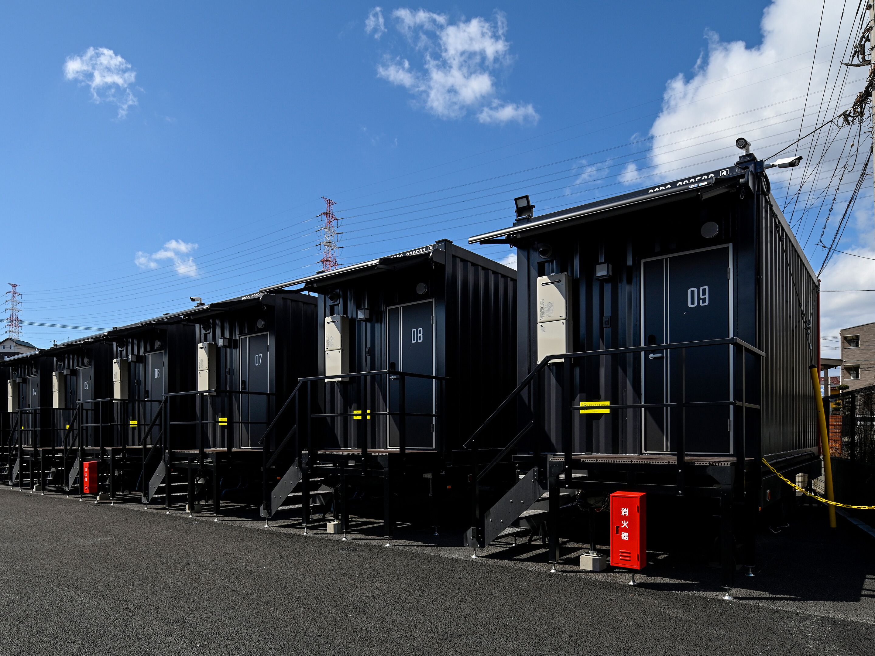 A row of black train carriages numbered 07 to 09, with steps leading up to the doors, and a red fire extinguisher visible on the right.