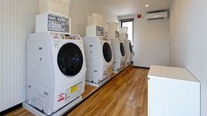 A row of front-loading washing machines in a laundry room with wooden flooring and white walls. - HOTEL R9 The Yard Fukuyama (Fukuyama)