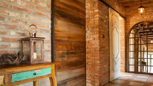 Um interior rústico com paredes de tijolos aparentes, painéis de madeira, um candeeiro antigo e piso xadrez.