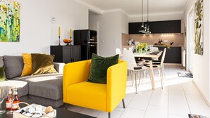 Una sala de estar moderna con un sillón amarillo, un sofá gris y un comedor con mesa y sillas.