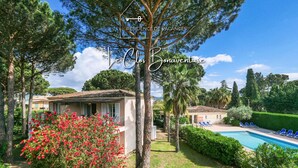 Une villa avec piscine, entourée d’une végétation luxuriante et sous un ciel d’un bleu éclatant.