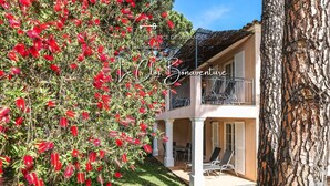 A two-story house with a balcony and a garden with red flowers. - Rêves de Provence 1 renovated vacation apartment Sea and beach 150 m away (Gassin)