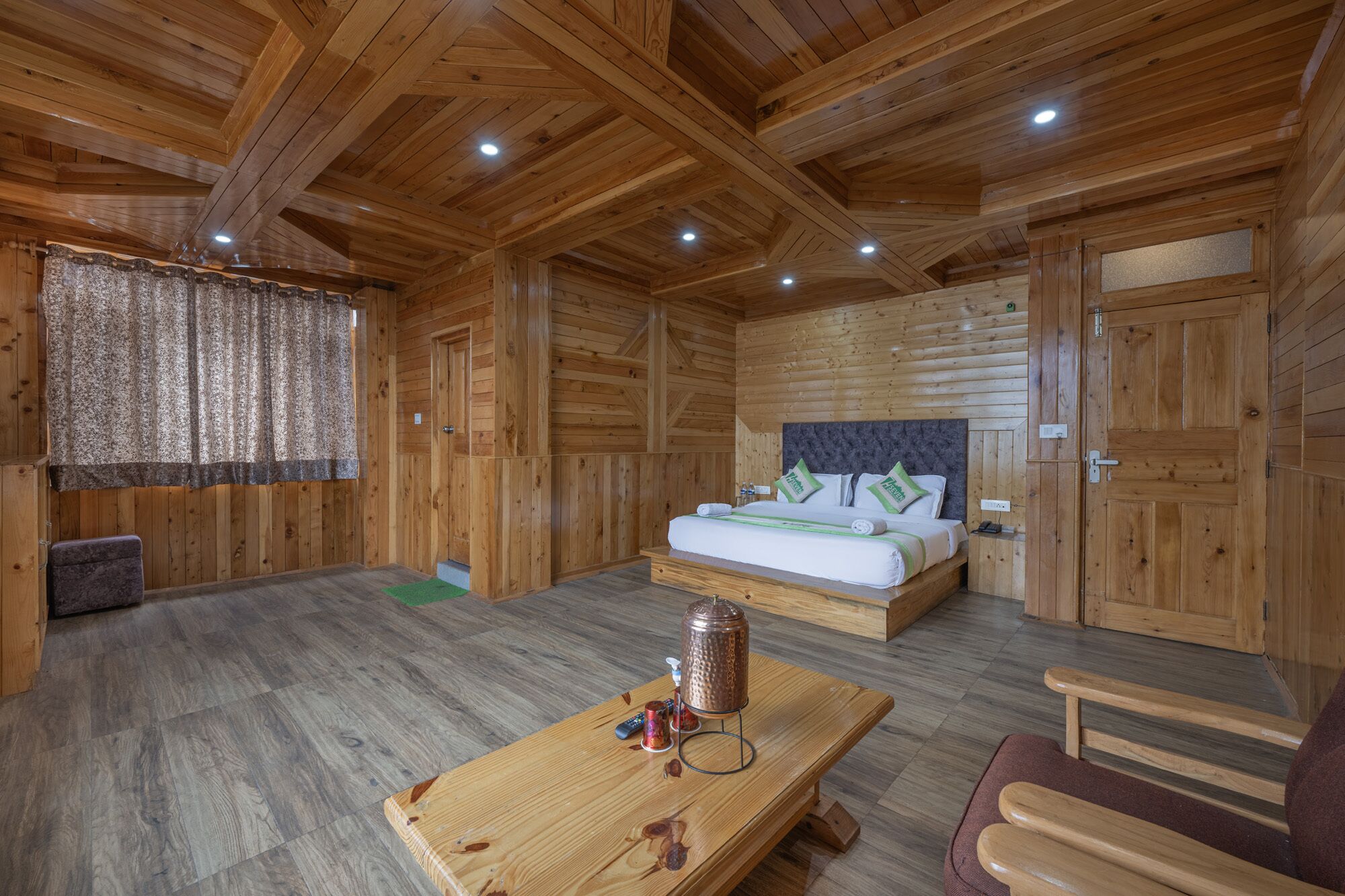 A wooden cabin room with a bed, a table, and a bench.